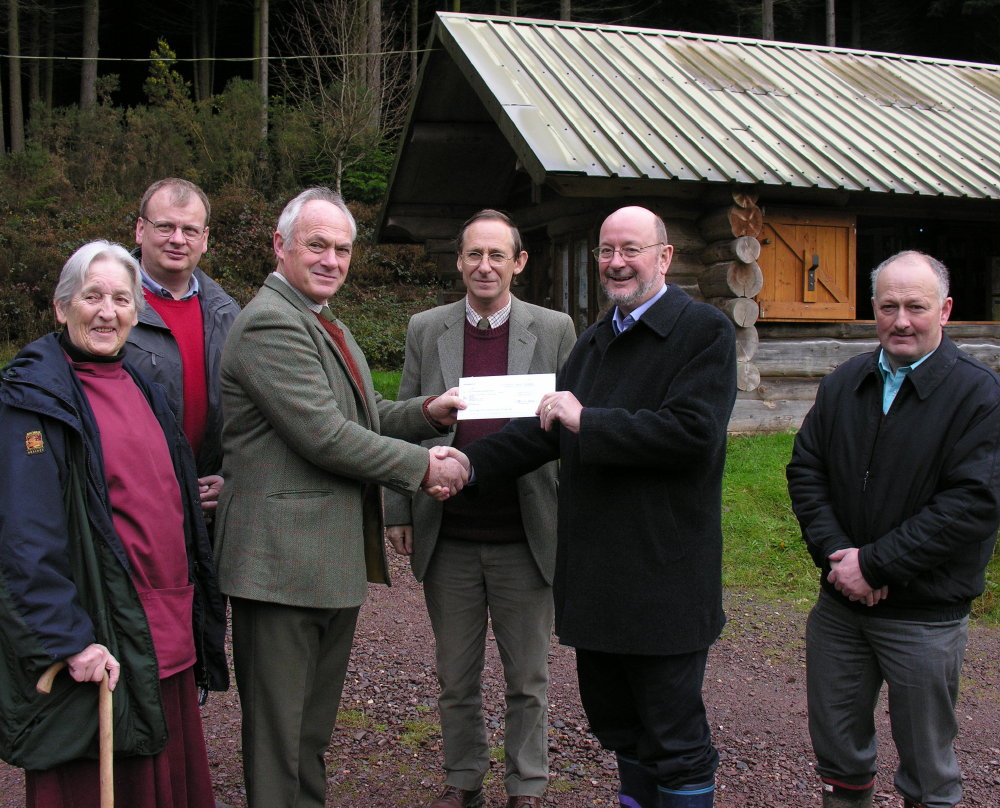 A cheque for $44,000 is presented to the Offwell Woodland & Wildlife Trust, in front of the Centre's Log Cabin.